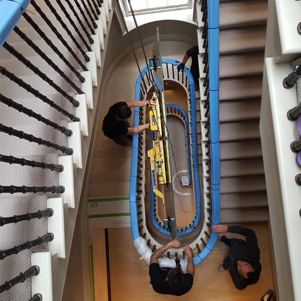 Heavy glass window being moved on stairs using specialist stair climbing equipment